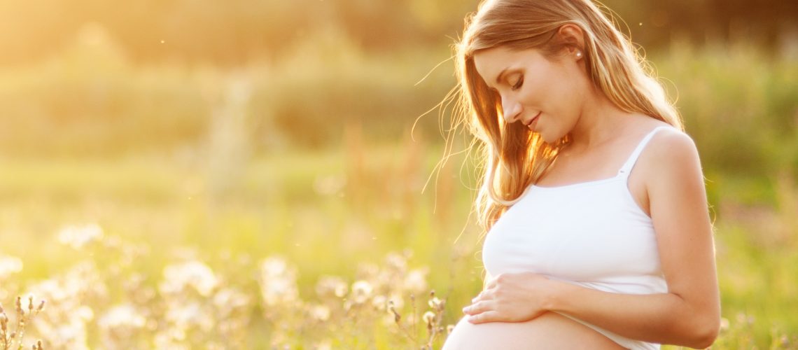 Beautiful pregnant woman relaxing outside in the park